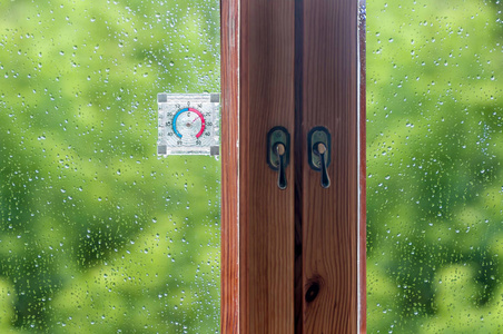 雨滴在一个木制的窗口和一支温度计，绿色高建群