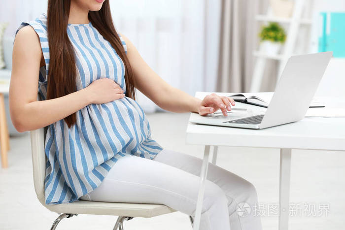 漂亮的年轻孕妇在家工作