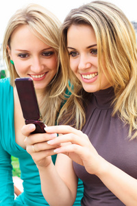 两个微笑的女孩在看手机里的东西