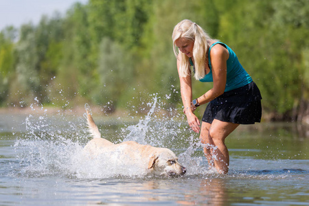 成熟的女人玩弄在湖中的一只拉布拉多犬