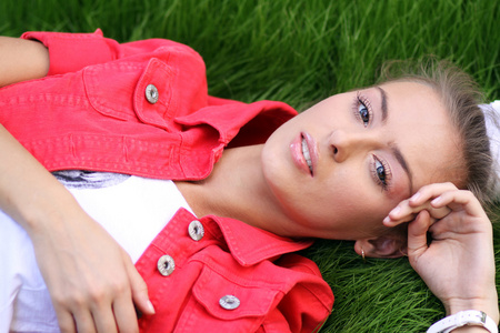 可爱的年轻女性躺在公园的草地上