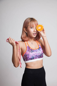 亚洲女孩健康饮食与橙色水果和卷尺