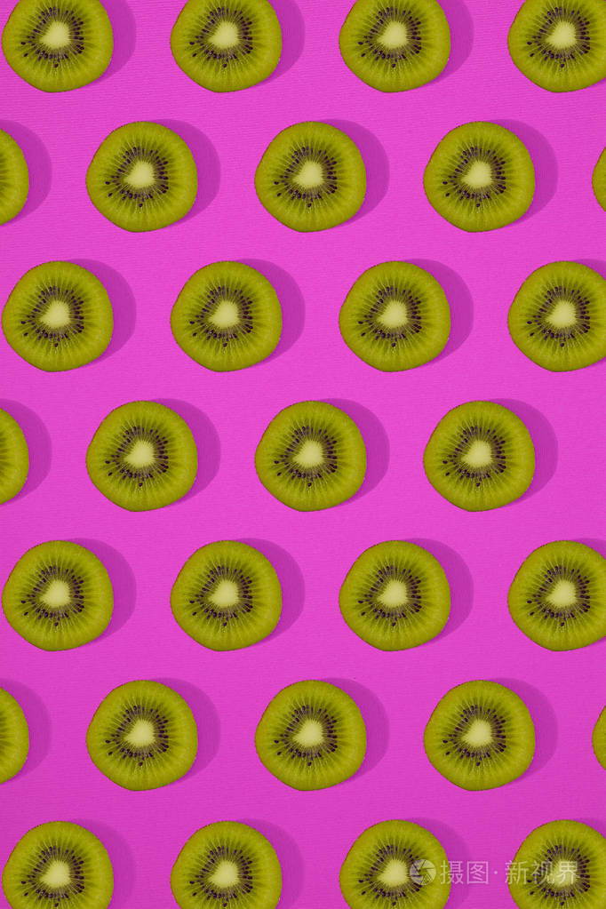 猕猴桃的图案。顶视图的切片的奇异果在粉红色的背景上。最小的平躺概念