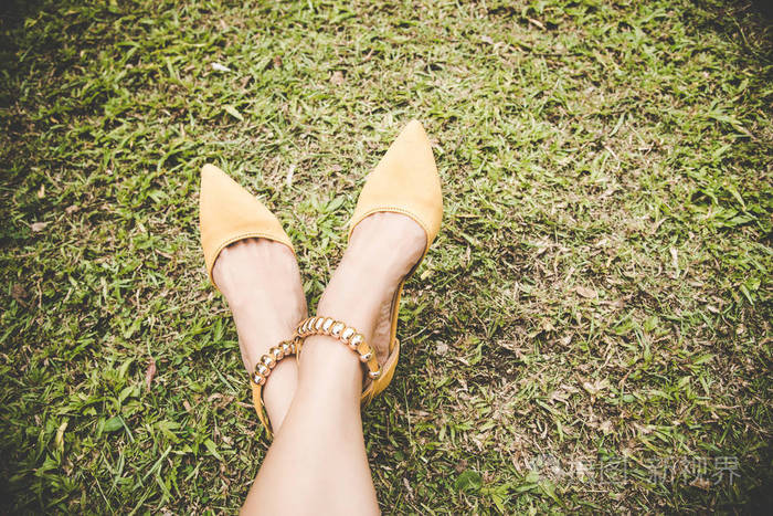 与时尚高跟鞋黄色与副本空间的绿色草地上的双腿.老式的口气.