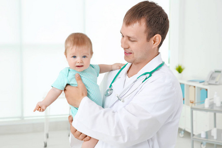 男性儿科医生抱着漂亮的女婴在室内