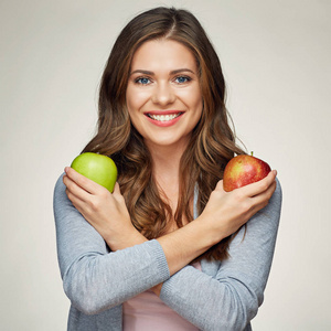 微笑的女人，拥有健康的牙齿，抱着两个苹果