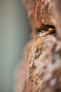 两个金色的结婚戒指在岩石的裂缝，结婚戒指背景概念