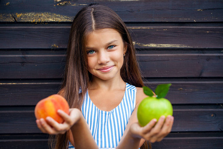 小女孩抱着一个绿色的苹果和桃子