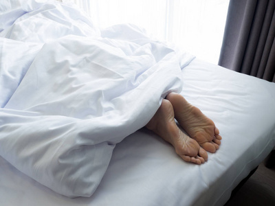 feet 的一名年轻女子躺在床上熟睡中的女人脚靠拢照片