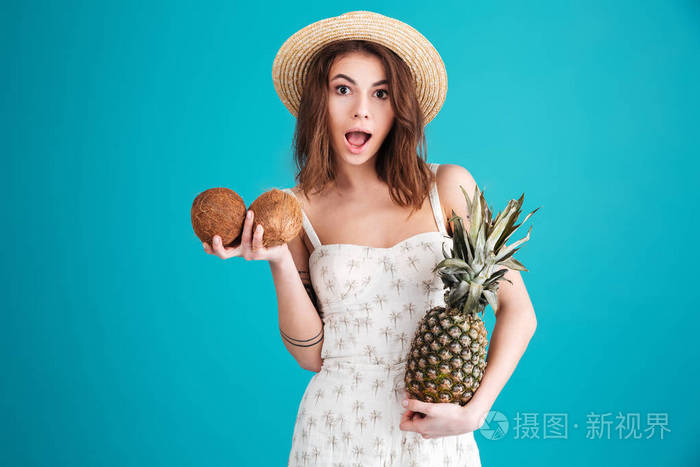 在夏天的衣服,抱着两个椰子和菠萝的女孩
