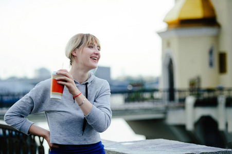 美丽快乐的年轻女子在城市里喝咖啡，笑着，享受生活