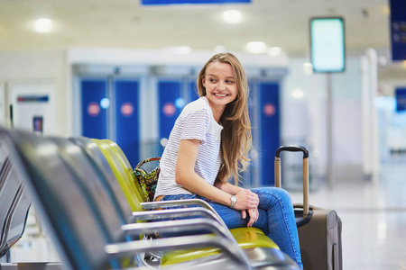 旅游的女孩背包和携带行李在机场，等待航班