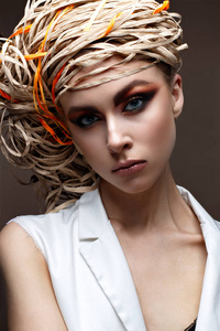 一个年轻的女孩，与明亮的创意化妆。漂亮的模特，带着她头上的草帽。纯的闪亮皮肤