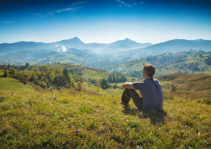 男人坐在小山上，享受谷