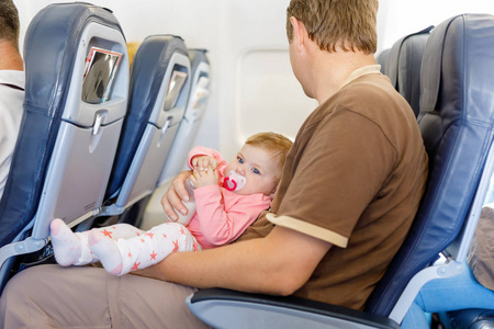 年轻疲惫的父亲在飞机飞行过程中携带他的宝贝女儿