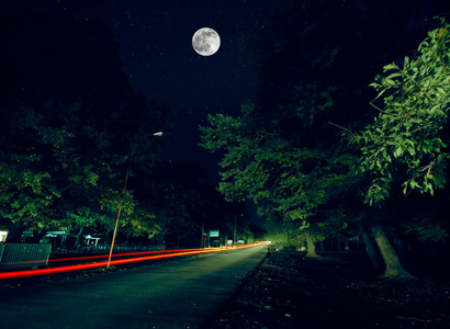 通过对月圆夜森林的山路。风景秀丽的夜景观的暗蓝的天空，月亮。阿塞拜疆