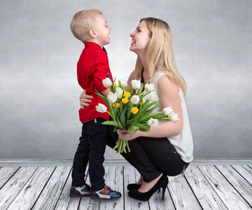小儿子给他心爱的母亲一束美丽的郁金香。春天，概念的家庭度假。妇女节