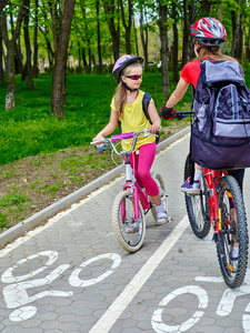 儿童女孩戴着头盔的背囊 ciclyng 骑自行车路径