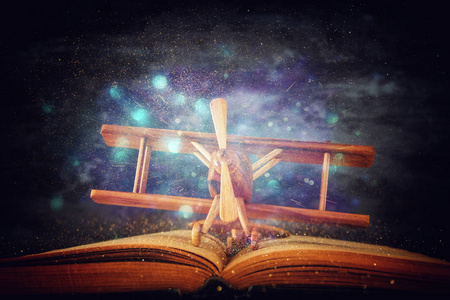 玩具飞机，打开的书上的木桌上闪烁的灯光