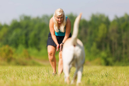 漂亮的女人和她的拉布拉多犬在户外玩