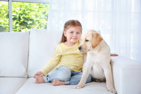 可爱的孩子与拉布拉多犬坐在沙发上