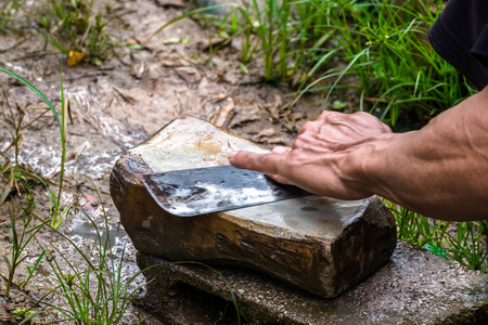 当地男性农民与磨刀石上磨刀