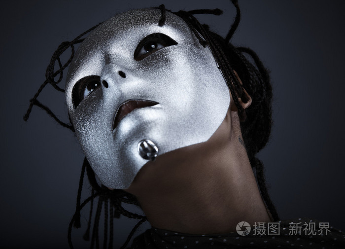 戴着银色面具的阴郁女人在黑色背景上摆姿势