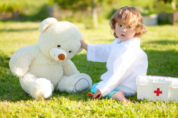 小女孩学龄前儿童玩玩具熊在户外的医生