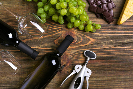 瓶子和眼镜的红酒，奶酪和成熟的葡萄，木制背景