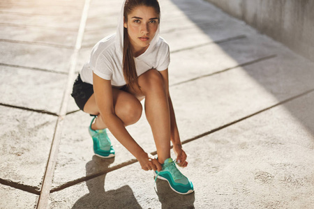 适合绑她的鞋带准备开始她早上慢跑在城市环境中的年轻女人。城市体育概念