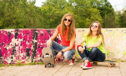 两个青少年女孩朋友玩乐和滑板。Outd