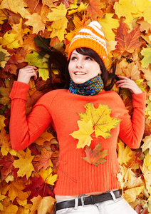 秋天橙色叶子的年轻女人。