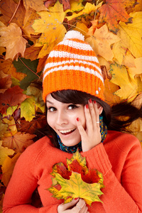 秋天的女孩戴着树叶上的橙色帽子。