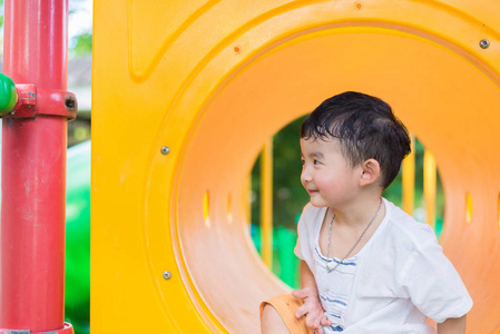 可爱的亚洲男孩玩和在黄色隧道在 playg 中微笑
