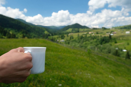 手与白杯咖啡山背景