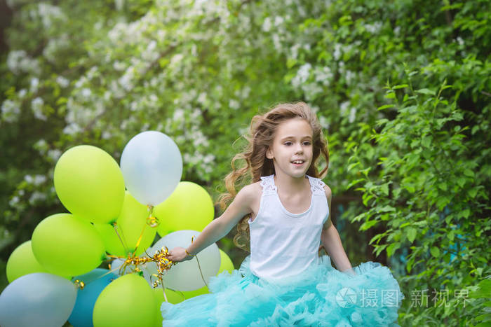 与长长的卷发，戴着智能蓬松裙子跑去会见一大堆的气球，欢笑着美丽的女孩。快乐的童年概念