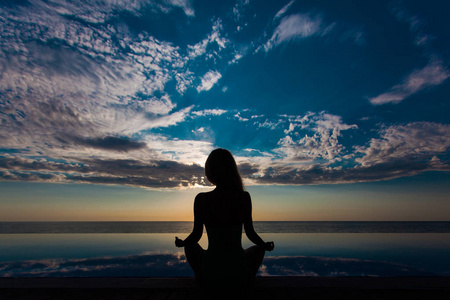 和健康的生活方式的背景下,抽象剪影的女人在游泳池和大海冥想照片