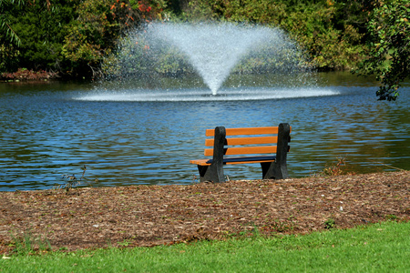 池塘上的喷泉和公园长凳