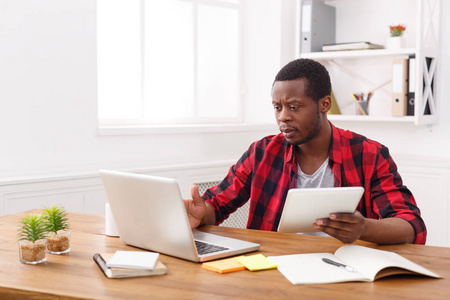 忧郁的年轻黑人快乐商人在办公室里，工作与笔记本电脑