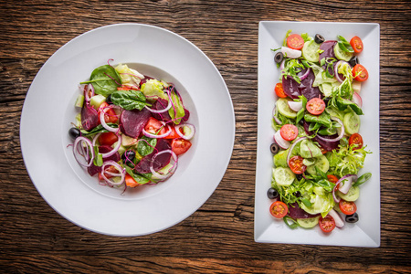 蔬菜沙拉。板的质朴的橡木桌子上的蔬菜沙拉。各式各样的蔬菜沙拉配料