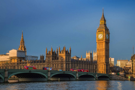 英国伦敦的大本钟和议会大厦威斯敏斯特桥上日出时的传统红色双层巴士