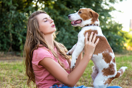 漂亮的女孩和一只小猎犬小狗一起玩