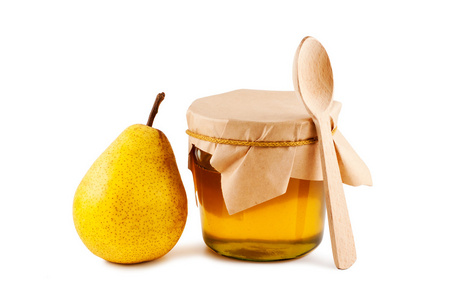 蜂蜜在玻璃罐里梨木勺子隔离在白色的背上
