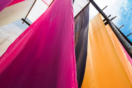 悬挂晾干后传统染色工艺的彩色织物照片