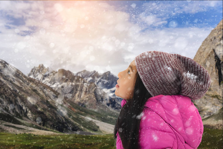 快乐的亚洲女孩穿粉红色羽绒服与雪山 bac