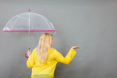 女人穿着雨衣打着伞检查天气图片