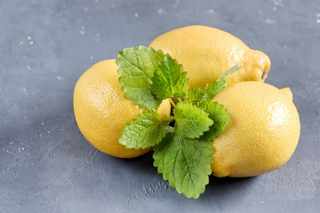 在切菜板上灰色背景柑橘薄荷叶的鲜黄色的柠檬