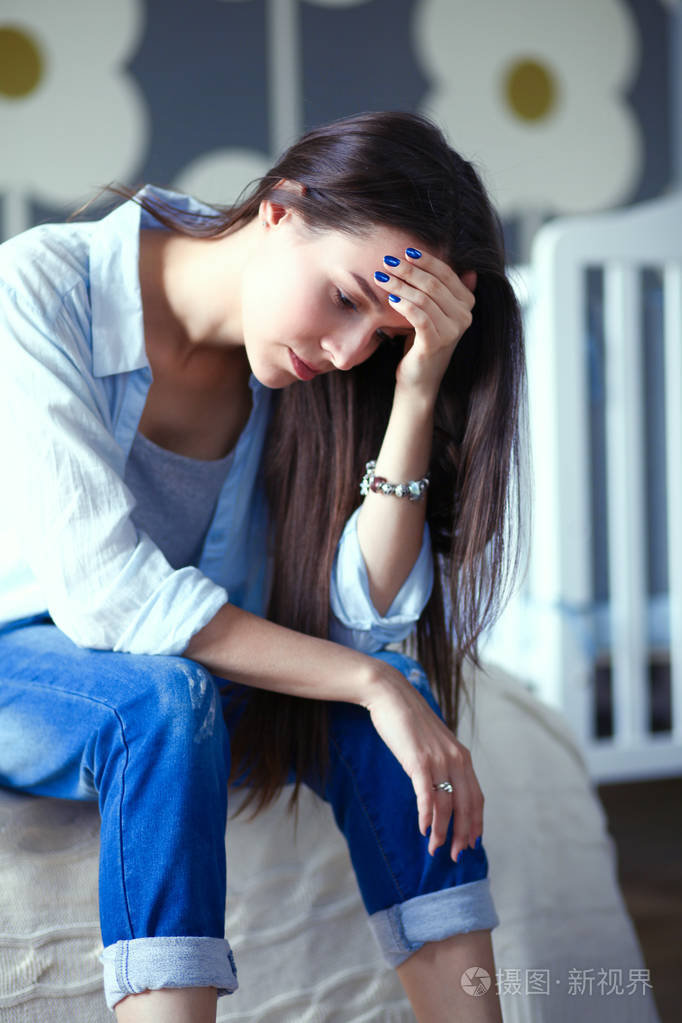 年轻累了坐在附近儿童床床上的女人年轻的妈妈