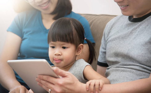 亚洲家庭坐和玩数字平板的幸福