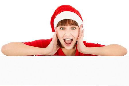 穿着圣诞老人红帽子的惊讶女人斜靠在空白广告牌上